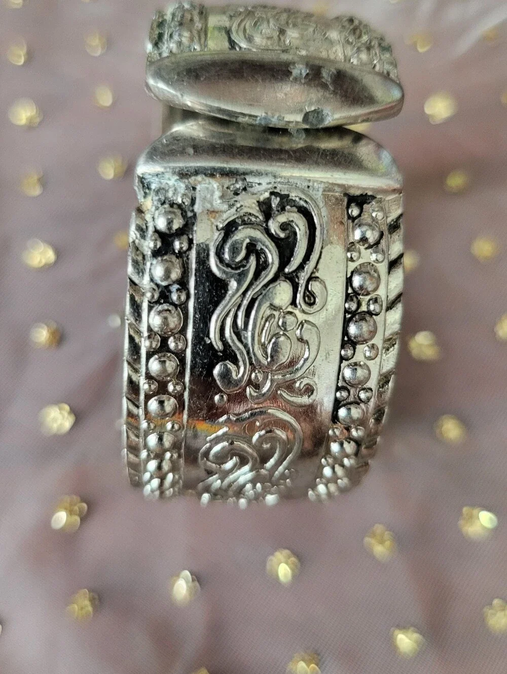 Silver bracelet watch with ornate scrollwork design has antique white face